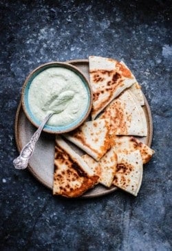 A plate filled with quesadilla wedges and a bowl of Roasted Poblano Cashew Cream Sauce.