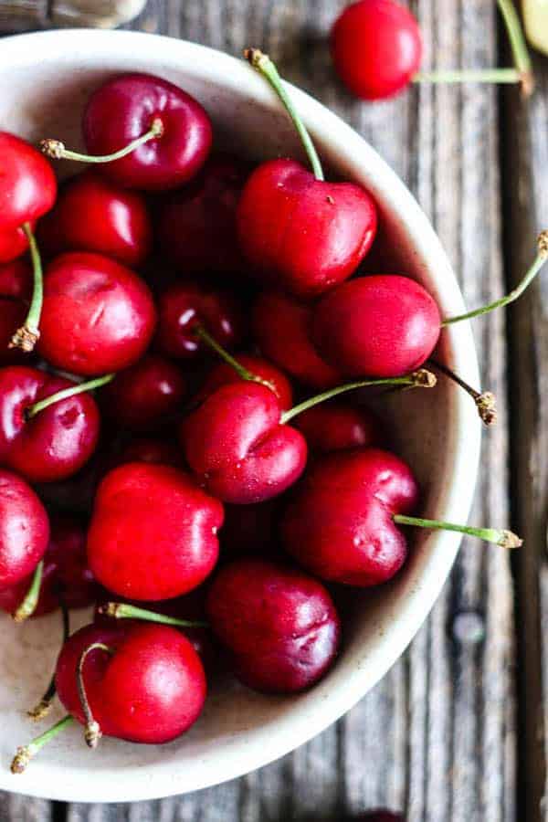 A close up of a bowl of fresh red cherries