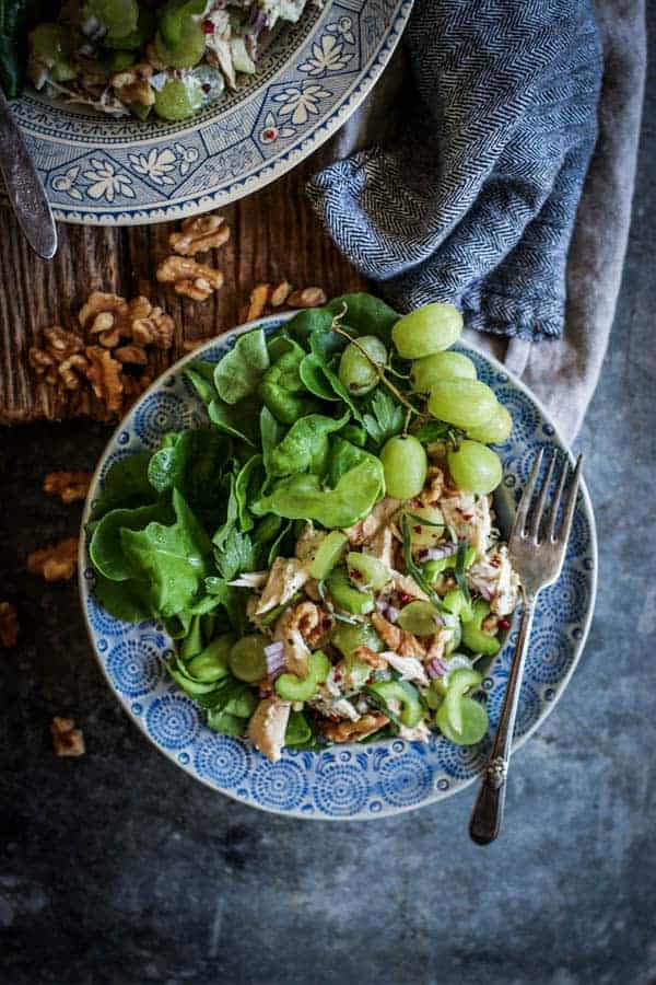 2 plates piled high with Easy Rotisserie Chicken Salad on top of butter lettuce leaves. The chicken salad has shredded rotisserie chicken, sliced green grapes, walnuts, celery, walnuts, and red onion toss din a Greek yogurt dressing