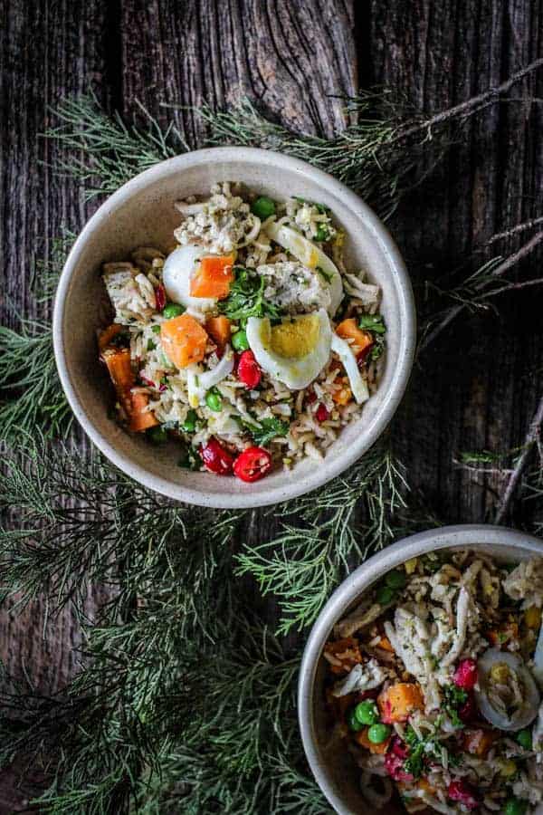 2 small bowls of home made dog food. The food has brown rice, sweet potatoes, cranberries, peas, turkey, herbs, hard boiled eggs, and hemp hearts