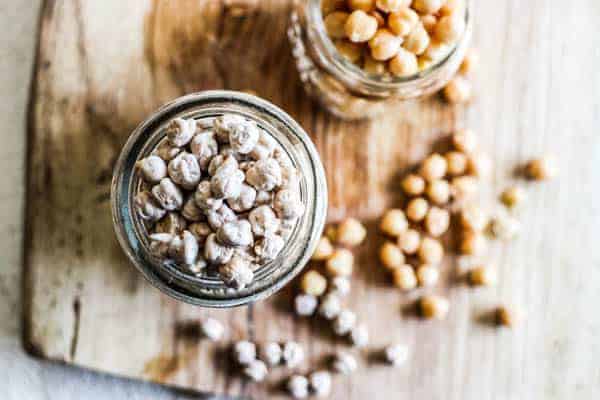 A top down image looking into 2 glass jars filled with garbanzo beans