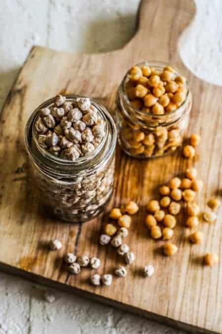 Looking down into 2 glass jars, once filled with dried chickpeas and one filled with canned chickpeas