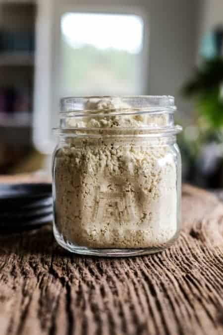 A glass jar filled with chickpea flour is sitting on a table.