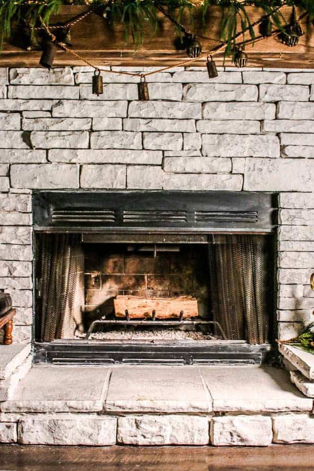 A fire place decorated for the holidays with a stack of wood inside it.