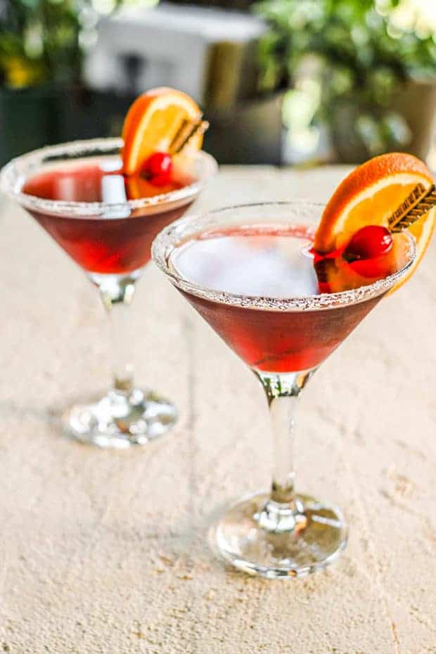 Two Super Antioxidant Martini on a table top with range wedge and cranberry garnish