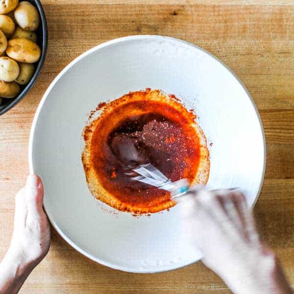 Whisking a red sauce in a white bowl
