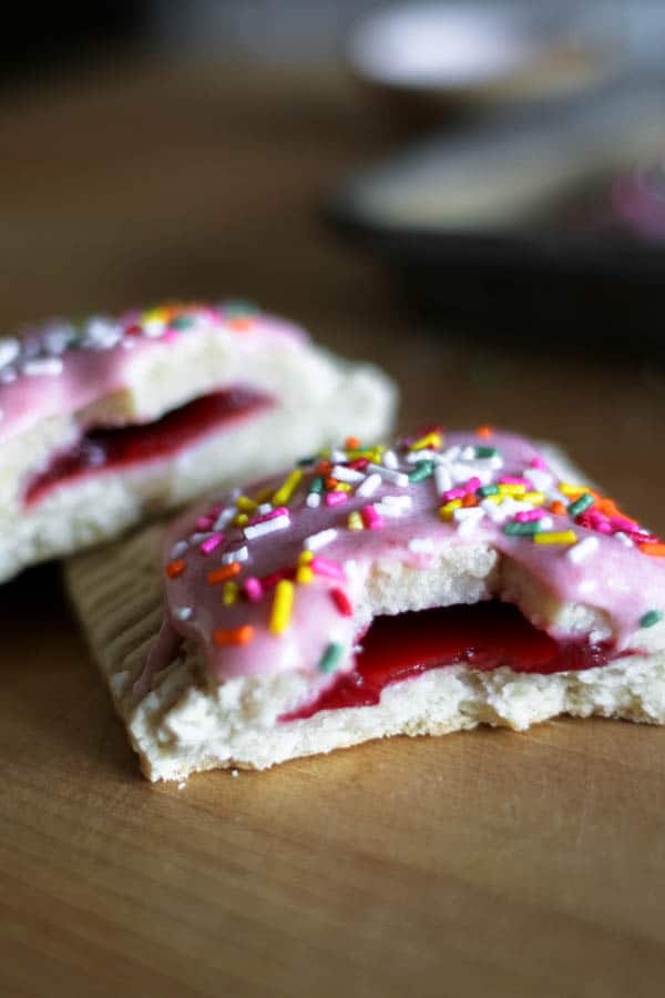 Two halves of a Gluten Free Strawberry Homemade Pop Tarts stacked on top of each other to show the filling