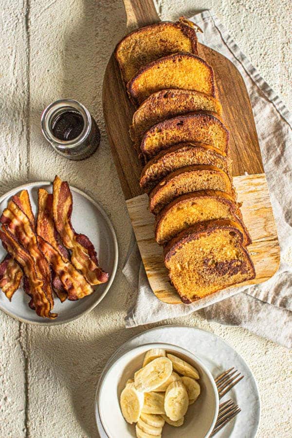 French toast, bacon, maple syrup, and fruit on a table