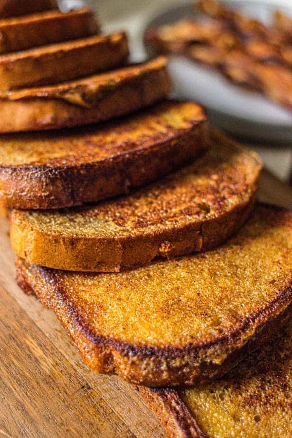 Pieces of French toast layered one on top of another on a serving board.