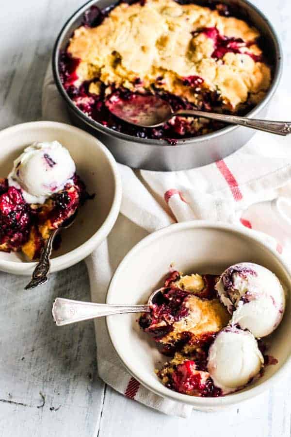 2 bowls of black & blueberry cobbler with scoops of ice cream ready to be served. 