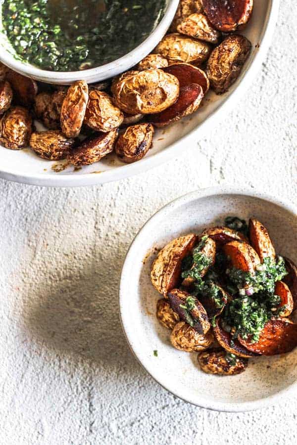 A bowl of crispy oven roasted potatoes topped with chimichurri