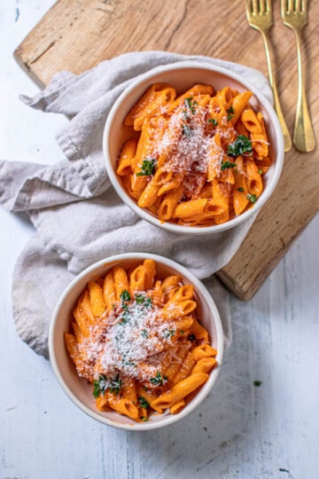 Two bowls of pasta tossed in 5-ingredient marinara sauce recipe and topped with chopped parsley and shredded Parmesan