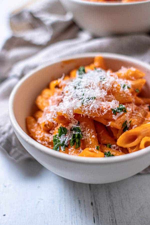 A bowl of pasta tossed with homemade marinara sauce and served with parsley and Parmesan