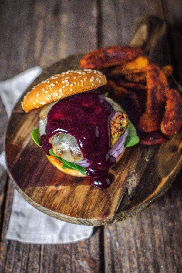 Our turkey burger recipe showcased on a bun with spinach, red onion, and jalapeño jack cheese. There is Blueberry Jalapeño Sauce dripping down the turkey burger.