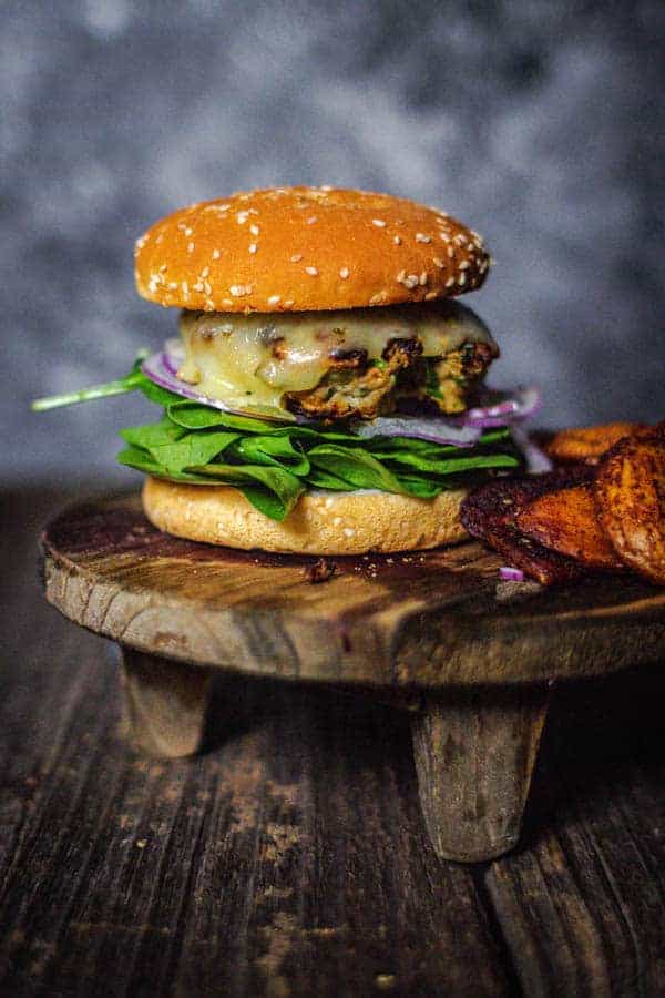 Showcasing our turkey burger recipe on a bun with fresh spinach, red onion, and jalapeño jack cheese