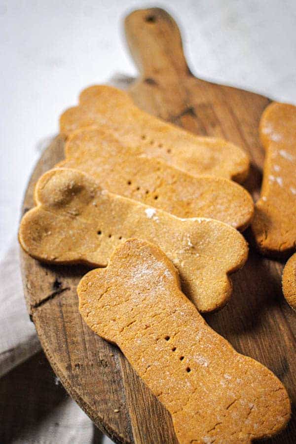 Peanut butter dog treats shaped like bones on a wooden tray