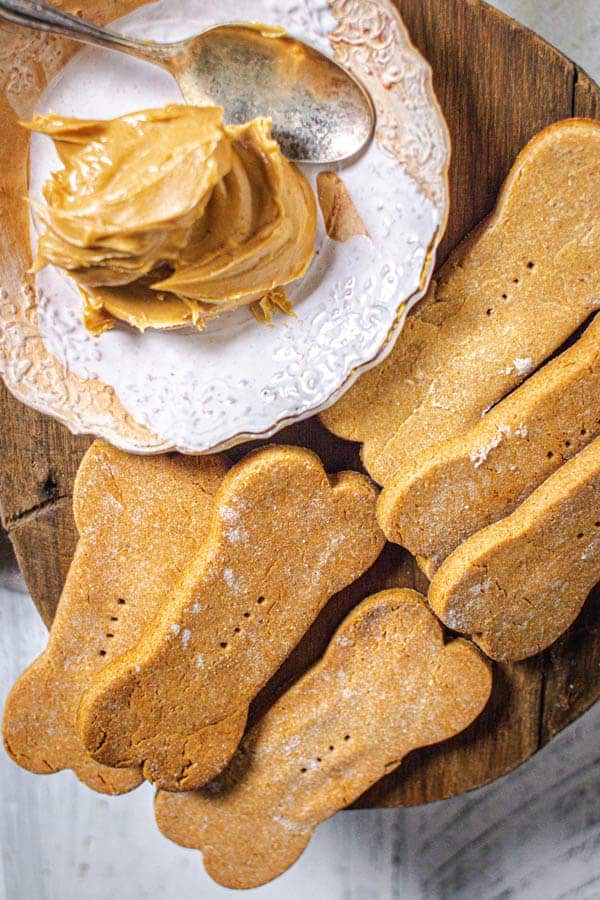 A close up of peanut butter dog treats next to a dish of peanut butter.