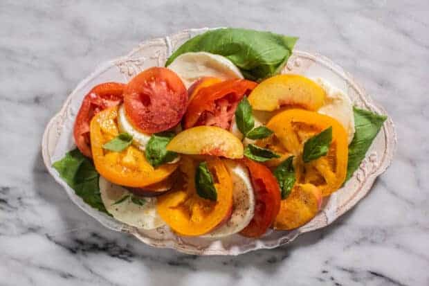 A plate of Caprese Salad with Peaches and Heirloom Tomatoes.