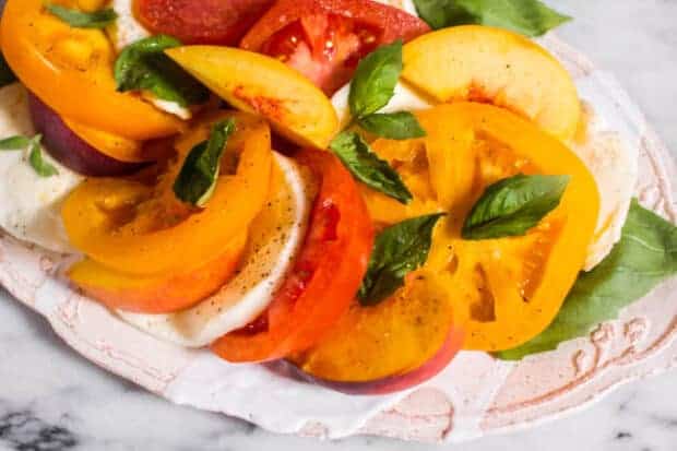 A plate of Caprese Salad with Peaches and yellow and red Heirloom Tomatoes.