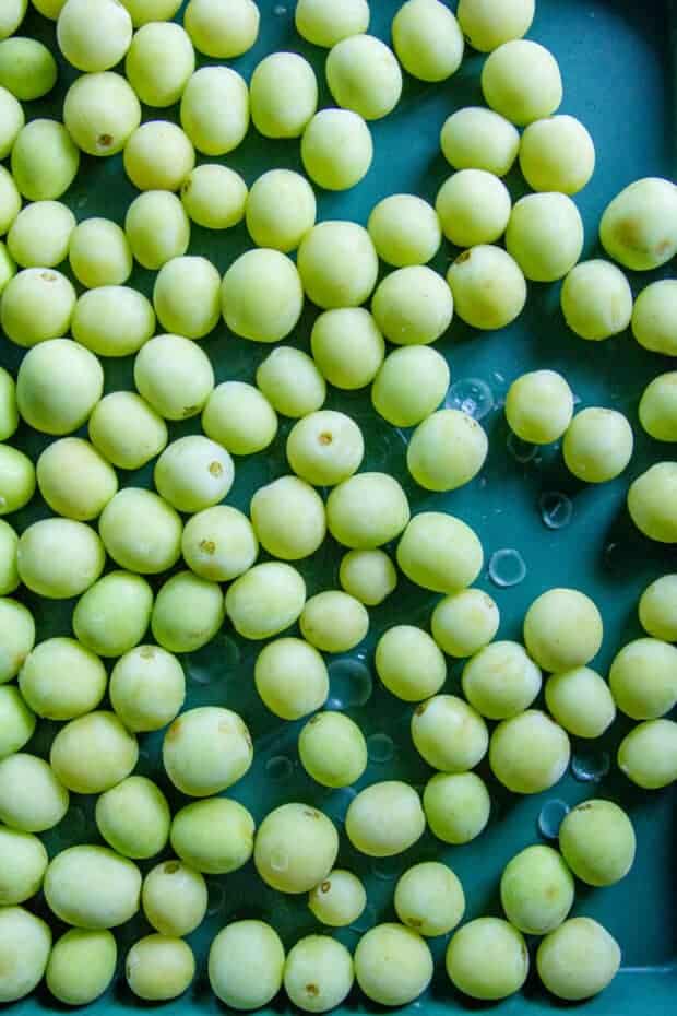 Frozen green grapes on a green sheet pan for making a recipe for grapes called Grape Nice Cream.
