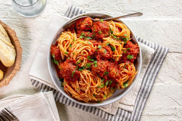 Sheet pan meatballs over spaghetti.