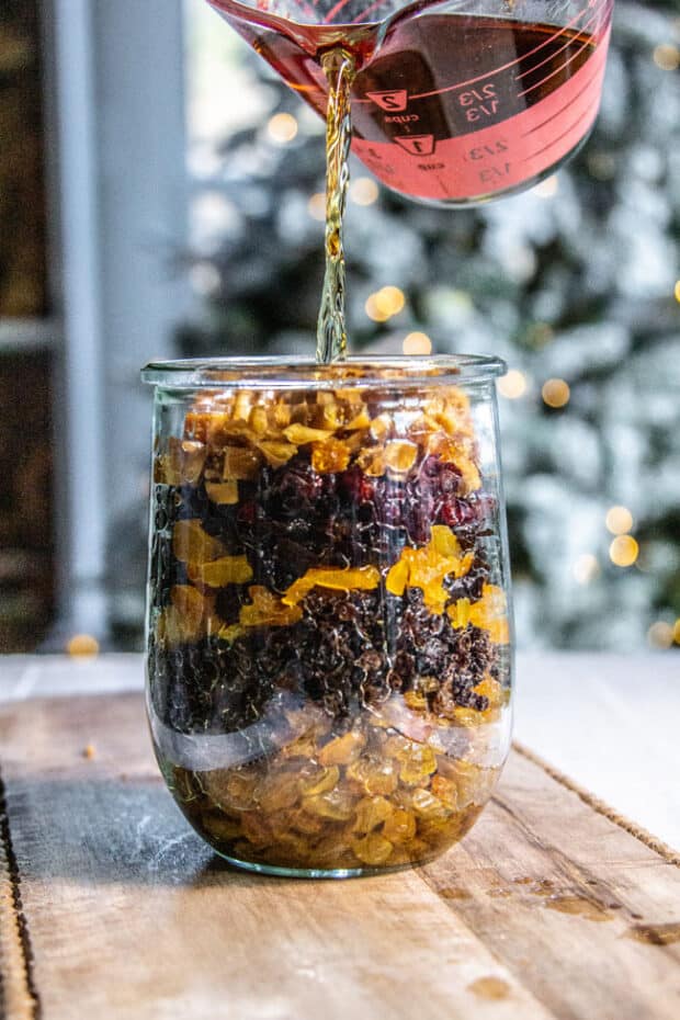 Booze being poured over dried fruit to soak for fruitcake.