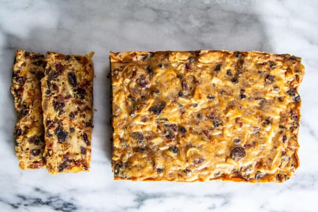 An Aged Gluten-Free Fruitcake Recipe With Citrus loaf with 2 slices cut from it on a marble slab.