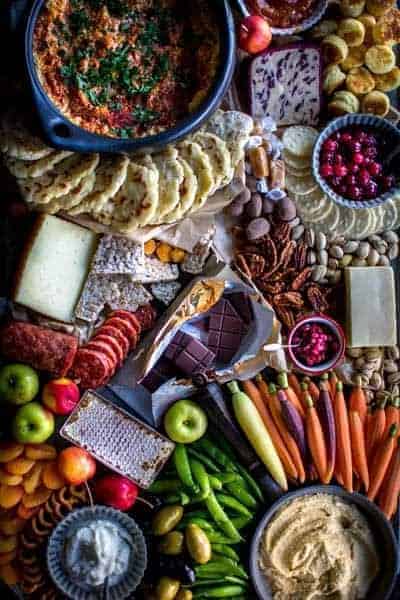A large dunk and slather board filled with a huge assortment of crackers, miniature biscuits, crudite, fruit, cheeses, charcuterie meats and dips.