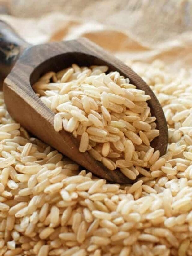 Wooden scoop full of brown rice.