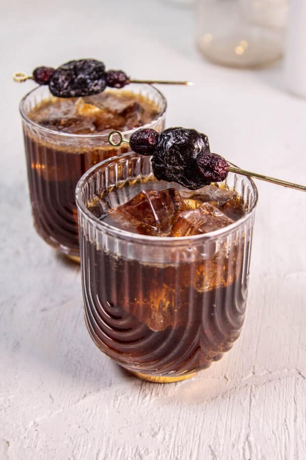 A Fruitcake Rum and Coke with a garnish of skewerd cranberries and a prune. The ultimate christmas cocktail.