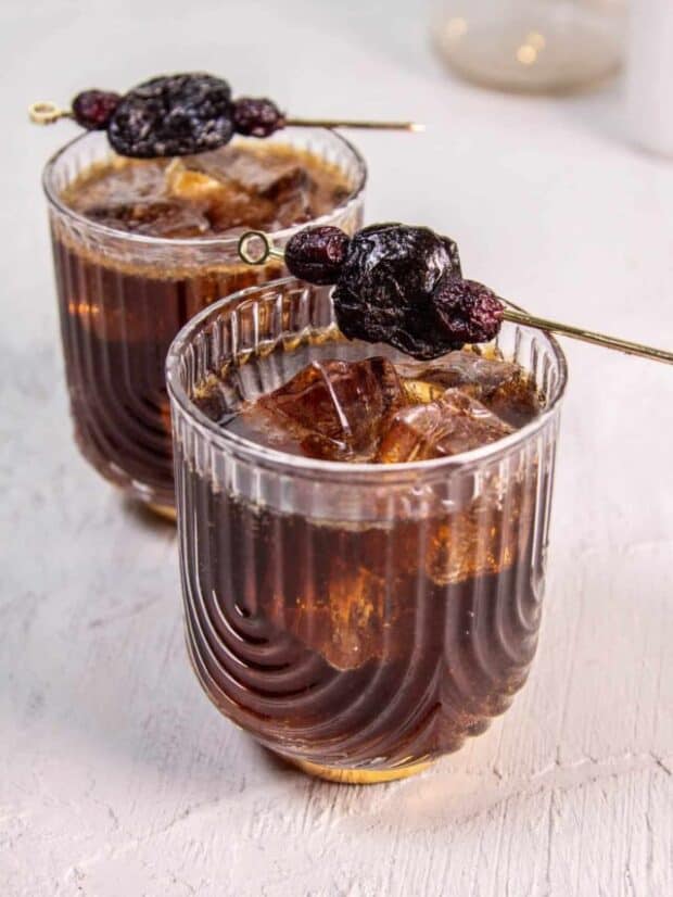 A Fruitcake Rum and Coke with a garnish of skewerd cranberries and a prune. The ultimate christmas cocktail.