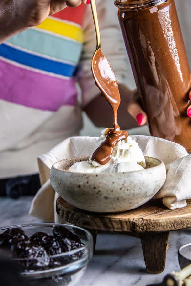 spoon pouring chocolate sauce over ice cream