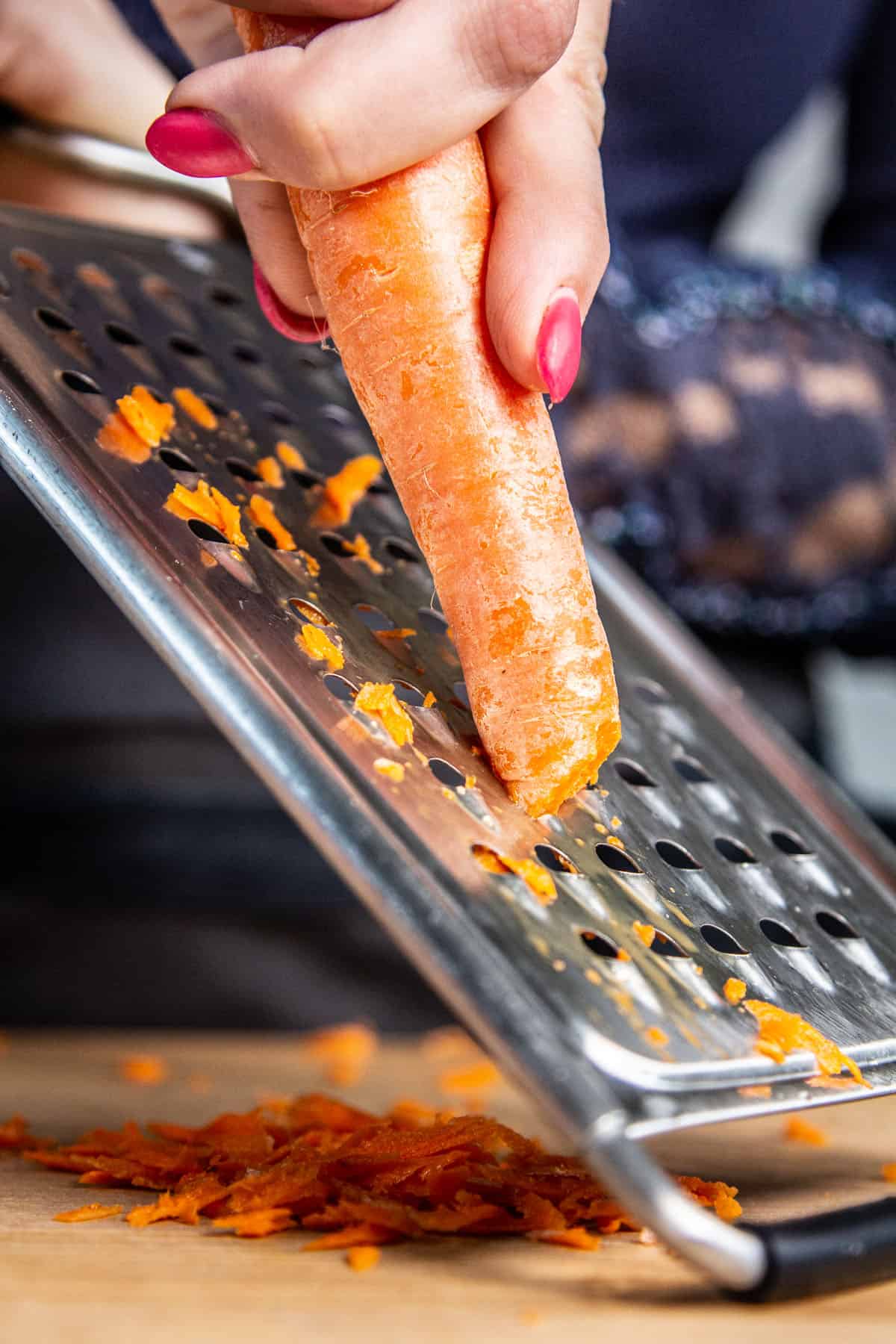 hand shredding carrot on grater 