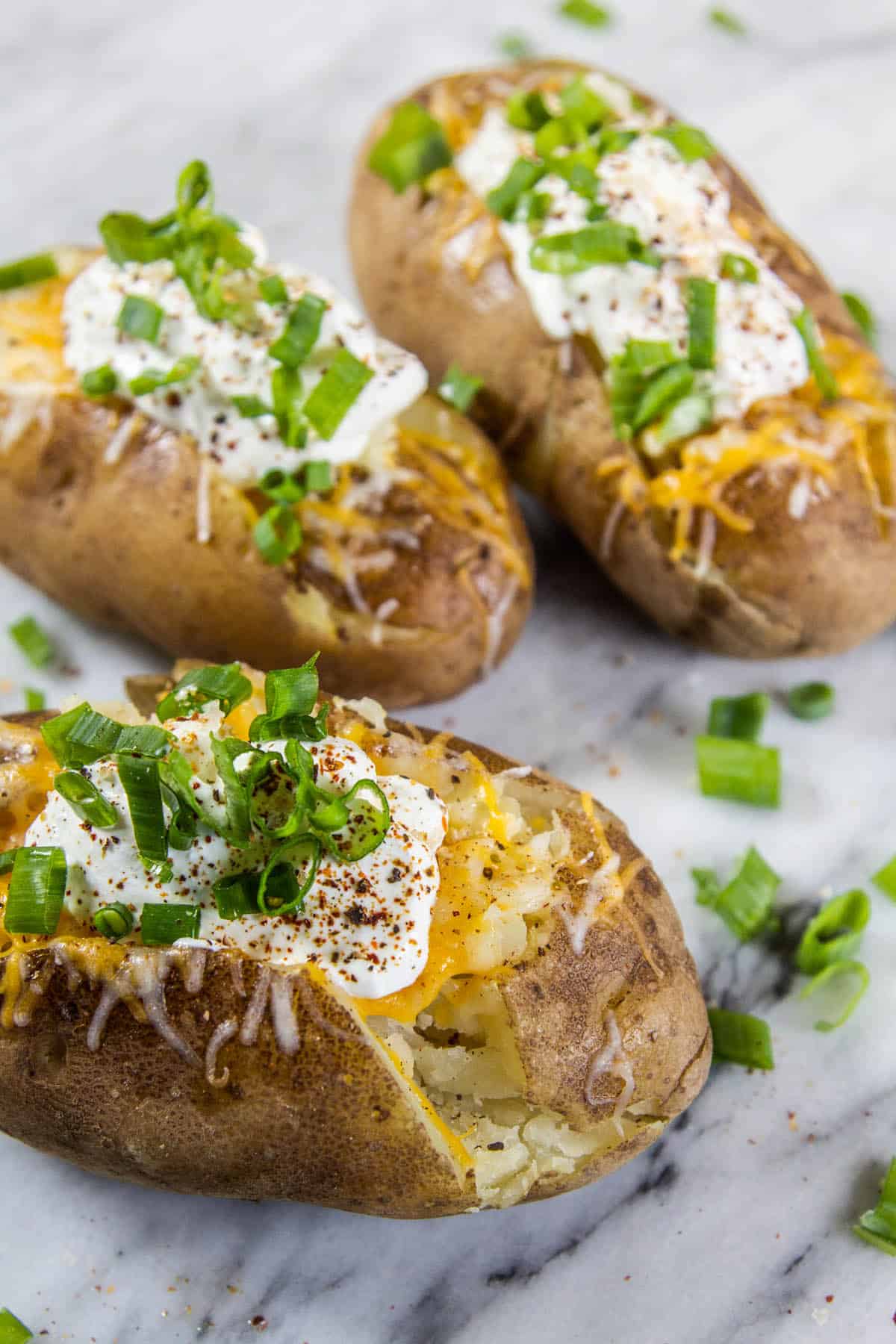 three baked potatoes on light background