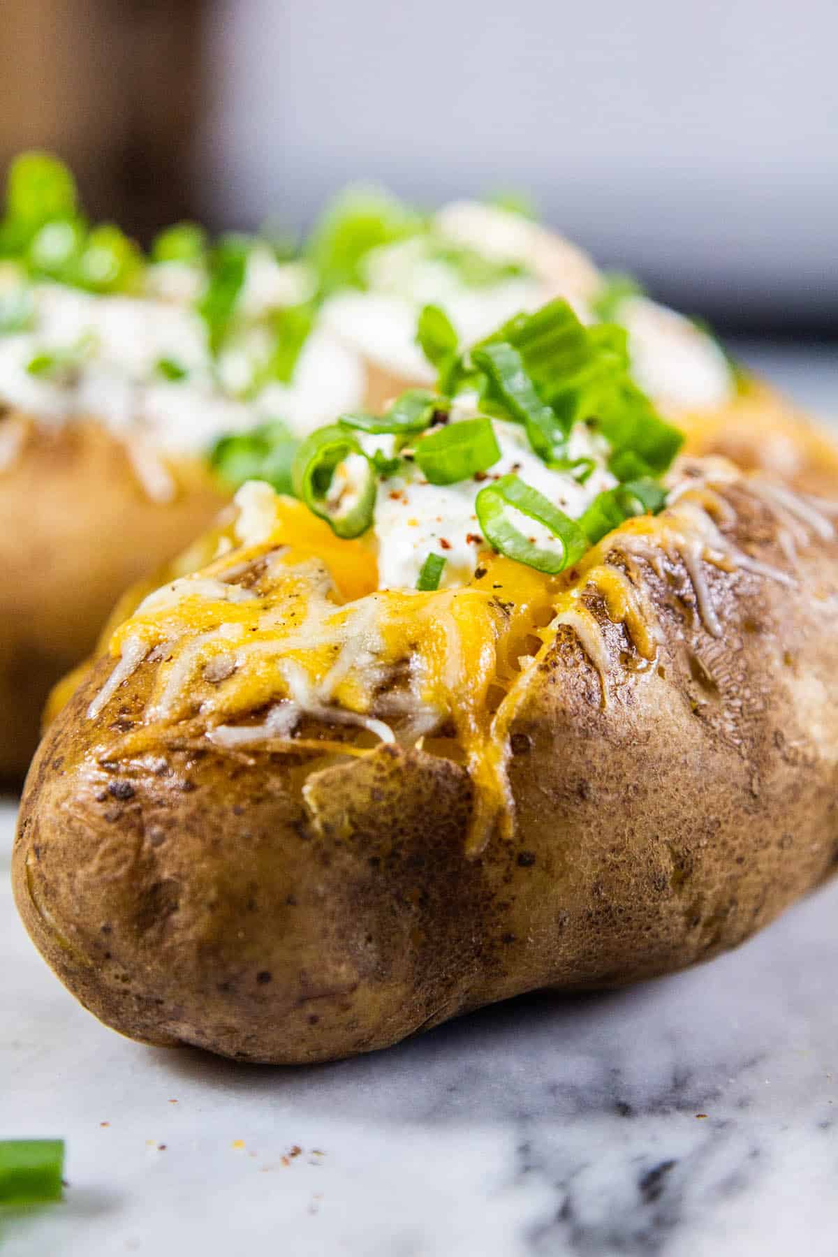 two baked potatoes on a marble board
