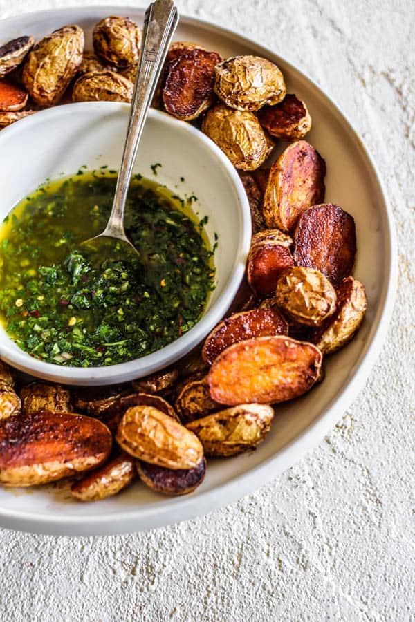 bowl of chimichurri surrounded by roasted potaotes