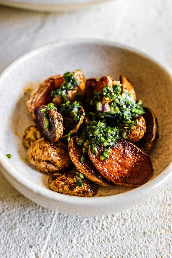 bowl of roasted potatoes with chimichurri sauce drizzled on top