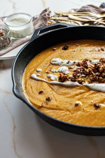 roasted sweet potato soup with pepita-apple-bacon brittle and lime-yogurt sauce in a skillet with spoons