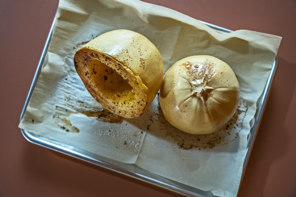 cooked spaghetti squash still in the gourd on a sheet tray lined with parchment paper