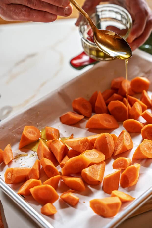 pouring olive oil on the carrots.