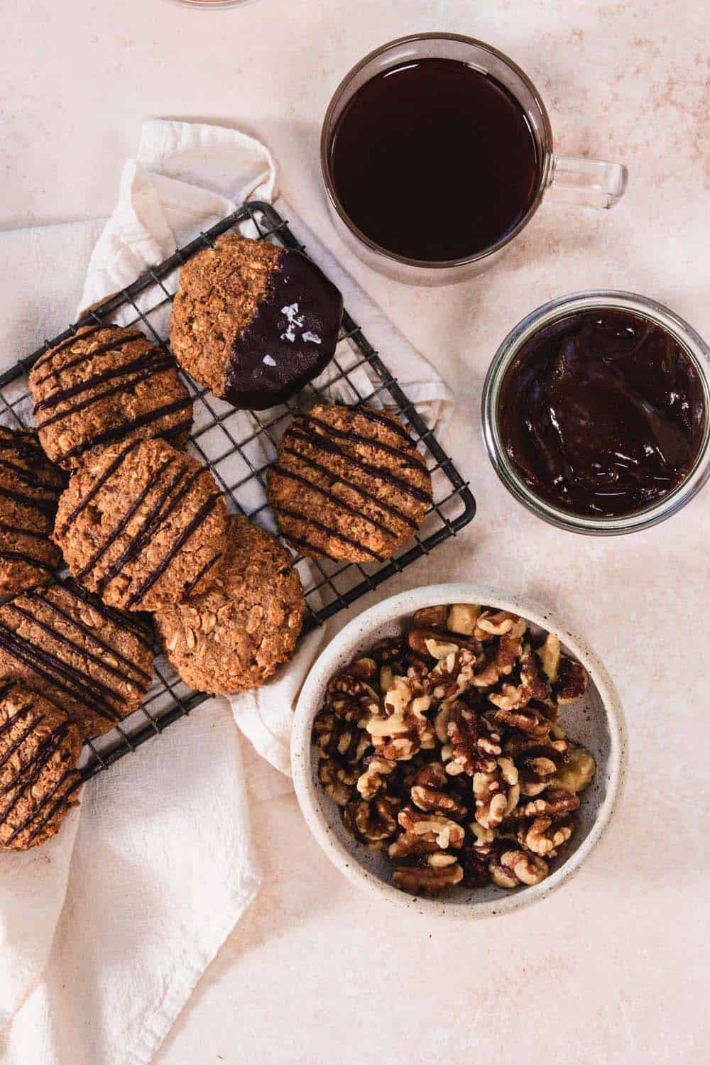 A bowl of walnuts, prune puree, and a mug of coffee next to cookies.