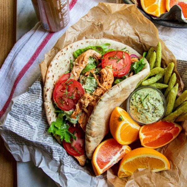 A pita bread stuffed with lettuce, tomatoes, red onion, tzatziki, and shredded Greek chicken.