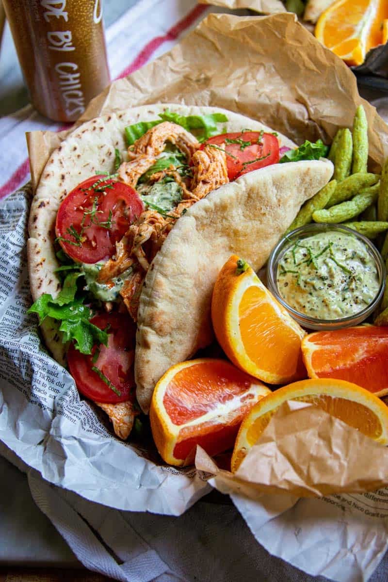 gyro greek chicken omn a plate with oranger a lemon slices and dried snap peas