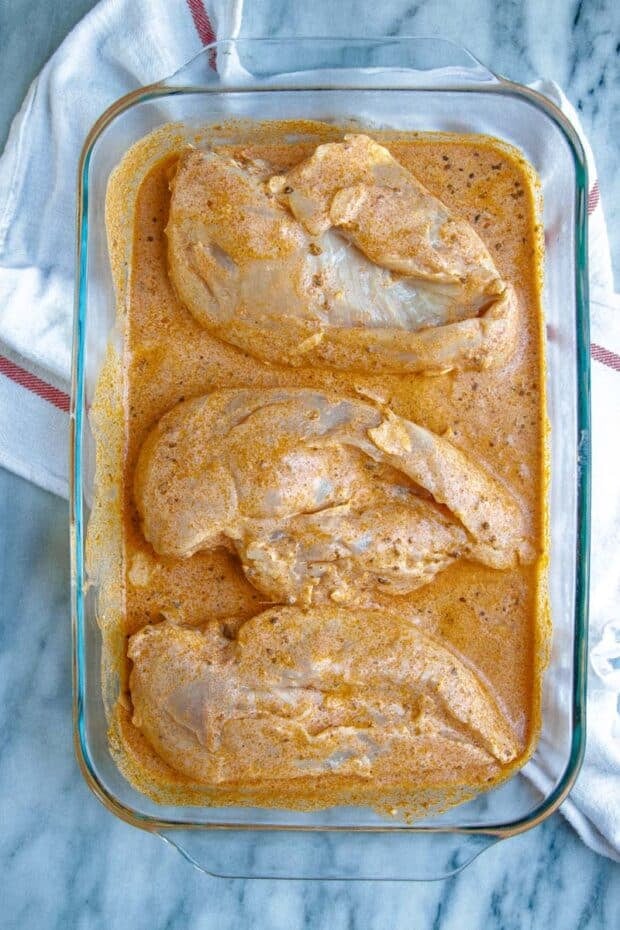 overhead shot of chicken breasts marinating in a glass container