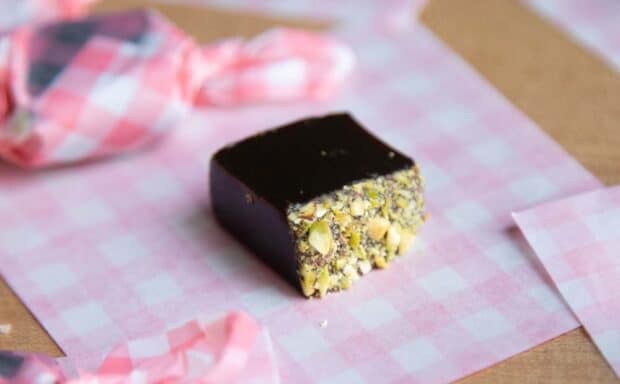 Close up of a dark colored caramel with crushed pistachios on top.